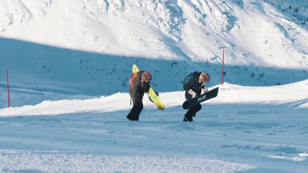 Horolezci držící snowboardy pohybující se vpřed na zasněžené hoře — Stock video