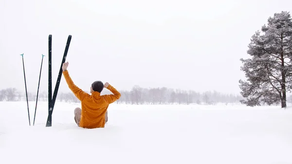 Visão traseira da pessoa sentada na neve com os braços esticados. Relaxar enquanto pratica desporto. Hobby esqui cross country no conceito paisagem inverno. — Fotografia de Stock