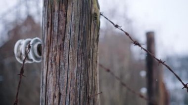 Closeup view of electric fence with barbed wires in Auschwitz Birkenau - Snow Fall