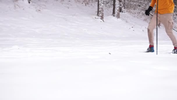 Filmagem de um esquiador masculino vestindo uma jaqueta amarela esquiando na paisagem nevada. — Vídeo de Stock
