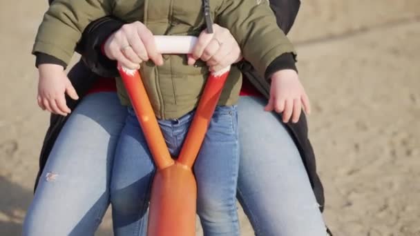 Beelden van een kind met zijn moeder genieten van de balancerende schommel in een buitenspeeltuin — Stockvideo