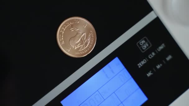 Vista de cerca de la moneda Krugerrand sudafricana se coloca en una escala de peso digital — Vídeo de stock