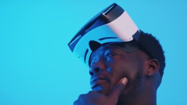 Alnında sanal gerçeklik gözlüğü olan Afro-Amerikalı bir adam etrafa bakıyor.