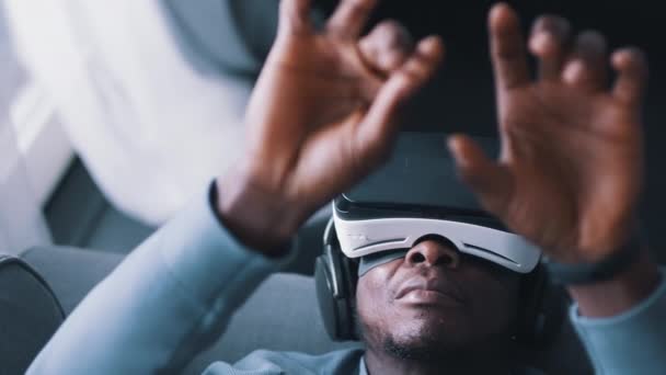 Афро-американец в очках виртуальной реальности и гарнитуре, касающейся воздуха руками — стоковое видео