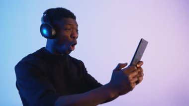 Elinde telefon tutan kulaklık takan Afro-Amerikalı bir adam.