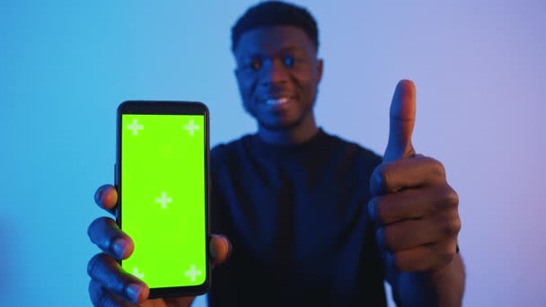 आफ्रिकन अमेरिकन ब्लॅक मॅन उभ्या हिरव्या स्क्रीनसह स्मार्टफोन धारण करीत आहे. थंब अप — स्टॉक व्हिडिओ