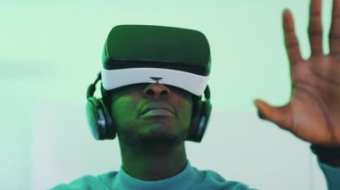 VR gözlük takan ve sanal gerçeklikte bir şeye dokunmaya çalışan adam.