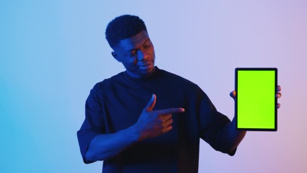 Hombre negro sosteniendo una tableta digital con una pantalla verde Apuntando a la tableta — Vídeos de Stock