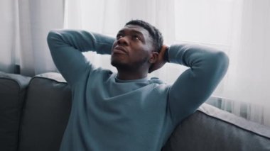 Mavi bir kanepede oturmuş düşünen ciddi bir adam.