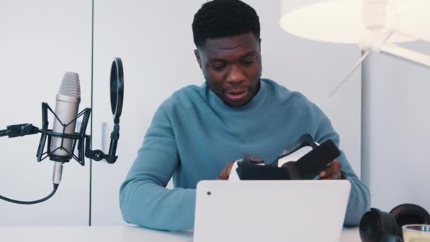 노트북 과 마이크를 들고 탁자에 앉아 VR 안경을 들고 있는 사람 — 비디오