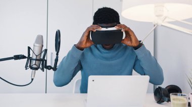 Bilgisayarının önündeki masada oturan sanal gerçeklik gözlüğü takan siyahi bir adam. Adam 360 derece sanal ortamda sanal gerçeklik gözlüğü kullanarak bir şey izliyor. Rahatlıyorum..