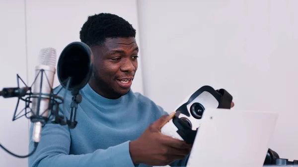 Elinde VR bardakları olan bir adam masada dizüstü bilgisayarı ve mikrofonuyla oturuyor. — Stok fotoğraf