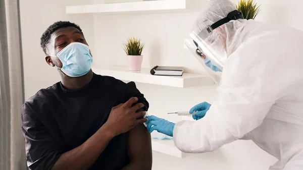 Covid-19 ya da koronavirüs aşısı. Vatandaşları aşılamak. Doktor elinde şırınga, yüzünde yüz ve maskeyle bir adama iğne yapıyor. — Stok fotoğraf