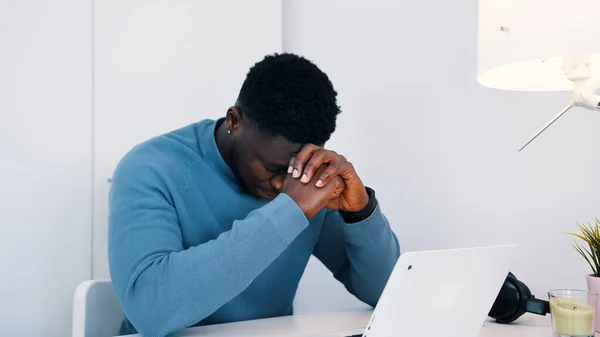 Αφροαμερικάνος μαύρος κάθεται στο τραπέζι μπροστά από ένα λάπτοπ και δουλεύει. Στρεσαρισμένος άντρας που δουλεύει στο λάπτοπ του.. — Φωτογραφία Αρχείου