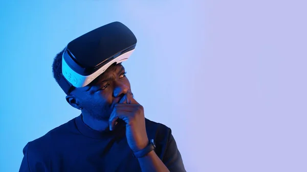 Афроамериканець з окулярами віртуальної реальності на лобі, що дивляться навколо. Дещо думаю. Віртуальні окуляри. Блакитний фон. Відеозапис. — стокове фото