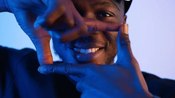 Um afro-americano a olhar para a câmara a fazer um quadrado com os dedos. Vista de perto de um cara sorridente fazendo uma moldura com as mãos. — Fotografia de Stock