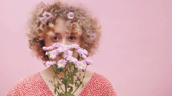 Porträt einer jungen kaukasischen Frau mit einem Strauß Frühlingsblumen über dem Gesicht und Blumenschmuck im lockigen Haar. Nahaufnahme — Stockfoto