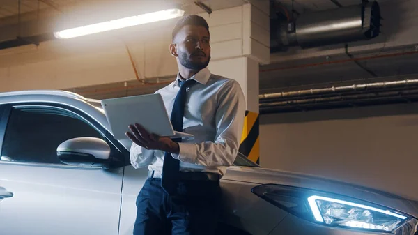 Businessman In The Parking Lot With A Laptop In His Hand Dressed In Formal Shirt