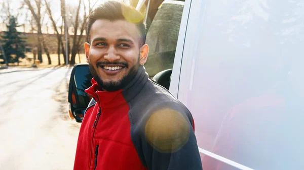 Delivery Guy Standing On The Road Smiling With A White Van Behind Him