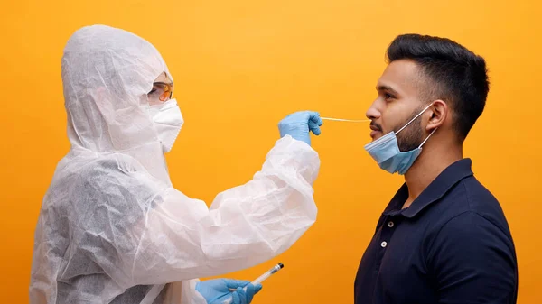 Travailleur médical en costume de protection prenant écouvillonnage nasal d'un homme potentiellement infecté — Photo