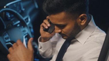 Stresli bir iş adamı arabasında otururken telefonda biriyle konuşuyor.