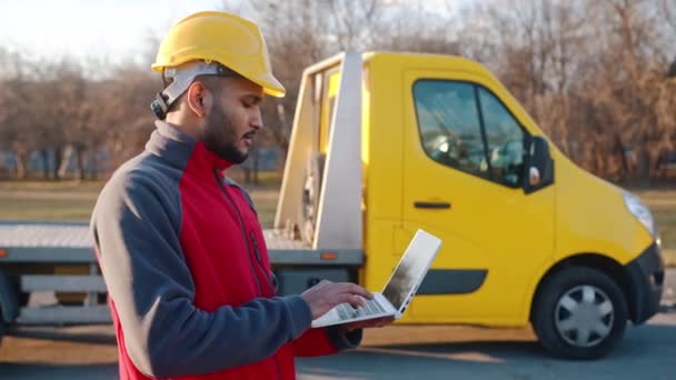 Jonge Indiase ingenieur draagt een veiligheidshelm met een laptop en werkt — Stockvideo