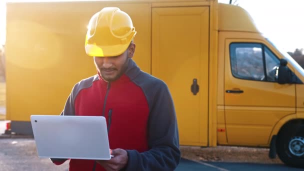 Mladý inženýr v bezpečnostní žluté přilbě drží notebook ve svých rukou — Stock video