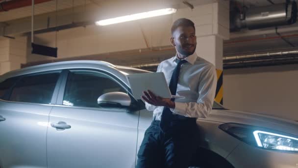 Homme d'affaires avec ordinateur portable dans ses mains - Voiture garée derrière lui dans le parking — Video