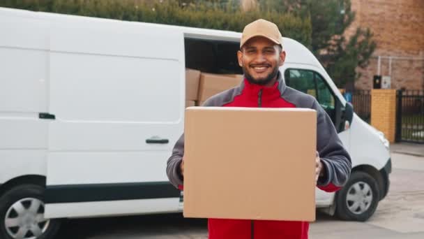 Bir paket taşıyan teslimatçı çocuk kutuyu kameraya doğru hareket ettiriyor. — Stok video