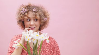 Bir demet beyaz Amaryllis çiçeği tutan kız gülümsüyor ve utangaç görünüyor.