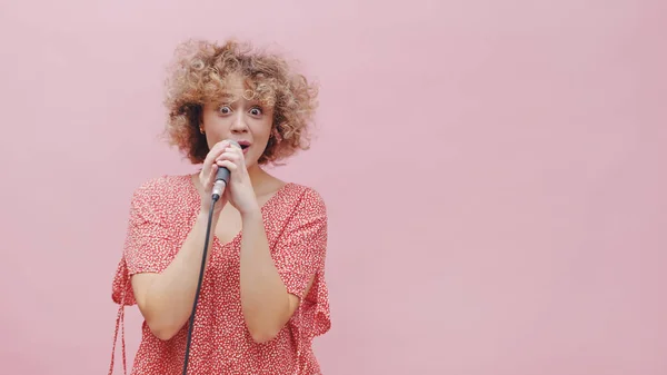 Menina cantando com um microfone - Menina olhando surpreso e animado segurando um microfone — Fotografia de Stock