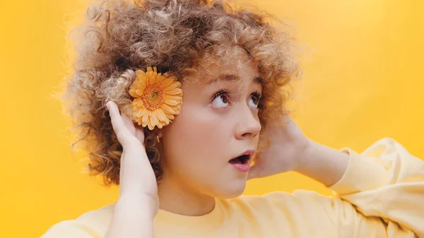 Menina com flor no ouvido tentando ouvir alguém com as duas mãos na orelha — Fotografia de Stock