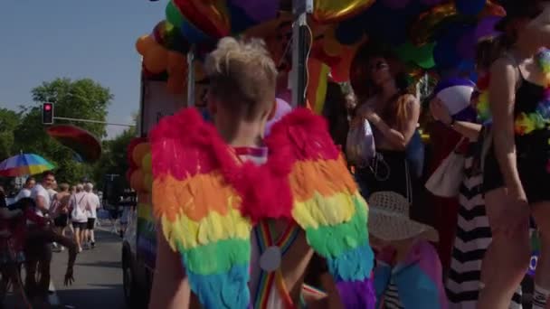 Caravana no desfile de orgulho LGBTQ, pessoas com asas coloridas de arco-íris de anjo e balões dançando — Vídeo de Stock