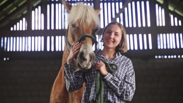Mladá dívka objímající krásného koně s Mane ve stáji - hladí koně — Stock video