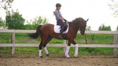 Kum parkında, tahta çit boyunca at süren bir kadın jokey.