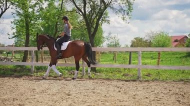 Koyu kahverengi atının sırtında at süren genç bir kız boş zamanlarında ata biniyor.