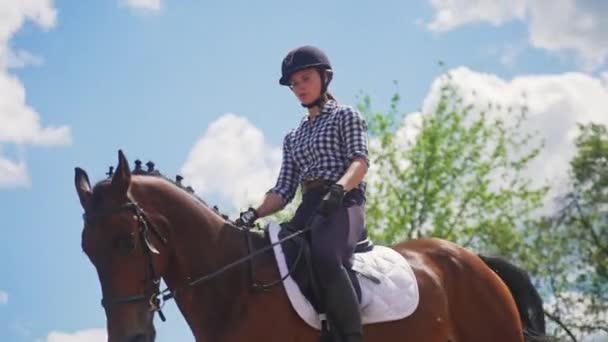 Kobieta dżokej w kasku jazdy na jej ciemnej zatoce konia - Chmurna pogoda — Wideo stockowe