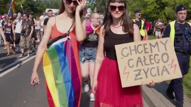 Two girls on the pride parade with rainbow fag and banner - We want life as a whole — Stockvideo