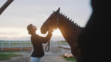 At sahibi Sandy Arena 'da gün batımında Seal Brown Horse' un dizginlerini tamir ediyor.