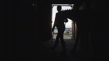 At sahibinin silueti atıyla gezintiye çıkıyor, ahırdan manzarası var.