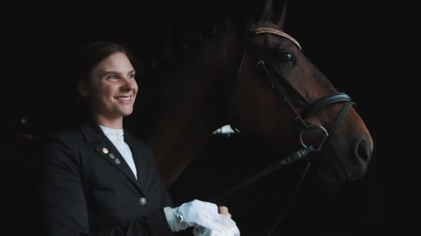 Horsewoman Standing With Her Dark Brown Horse Smiling And Putting On Her Gloves — Stock Video