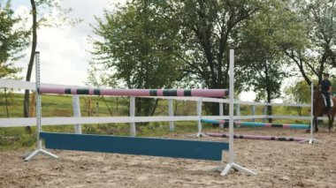 Koy atında koşan bir jokey, at bacağının çarptığı engellerin üzerinden atlıyor.