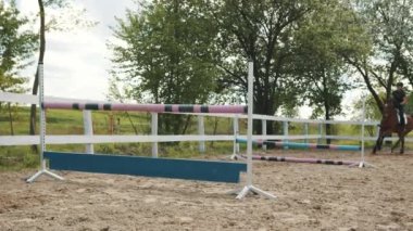 Karanlık körfez atına binen kadın jokey Sandy arenasında engellerin üzerinden atlıyor.