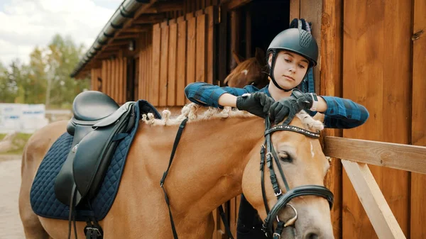 Feminino jockey fixação freio de ela luz marrom cavalo fora o estábulo — Fotografia de Stock