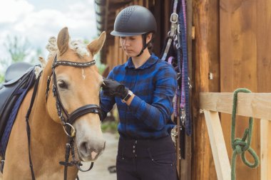 Açık kahverengi atlı jokey yarışmaya hazırlanan dizginleri tamir ediyor.