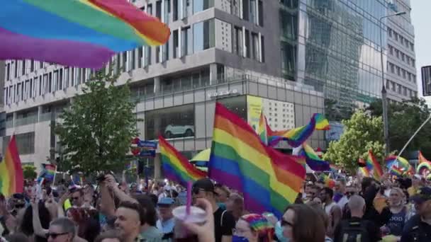 La gente ondeando las banderas del arco iris LGBTQ en el desfile del orgullo por los derechos LGBTQ en Varsovia — Vídeos de Stock