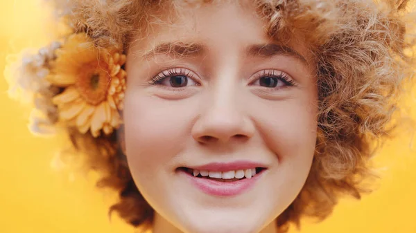 Gyönyörű lány göndör hajjal és narancssárga Gerbera Daisy virág a fülén mosolygó — Stock Fotó