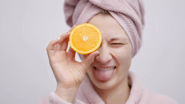 Joyful Girl Cover haar oog met de sinaasappel slice - concept van hydraterende huid — Stockfoto