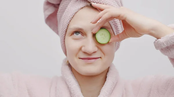 Mooi meisje holding een komkommer slice en bedekken haar oog met de komkommer — Stockfoto