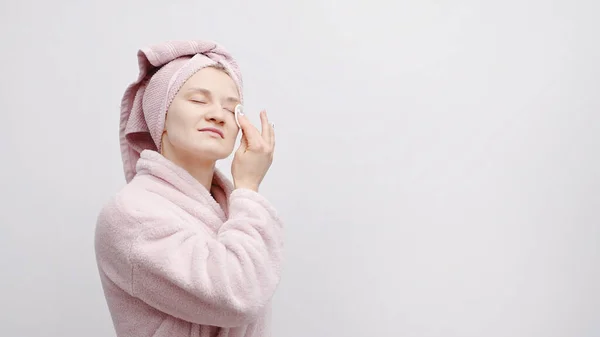 Mooi meisje met een hoofd handdoek verwijderen van make-up met behulp van een ronde witte katoenen pad — Stockfoto